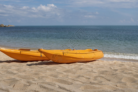 沙滩上的两艘彩色橙色皮划艇在阳光明媚的日子里为桨手做好准备 在沙子的几艘橙色消遣小船 活跃的旅游和水上娱乐 海 运输背景