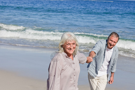老年夫妇在海滩上散步 衣服 灰色的 男人 微笑 女性背景图片