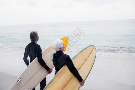 穿着湿衣的老夫妇在海滩上持冲浪板 自由 亲密感高清图片