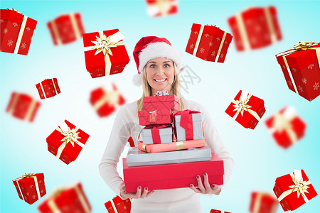 穿着圣塔帽的女人拿着一堆礼物 对抗数字制作的礼品盒 在她周围飞来飞去背景图片