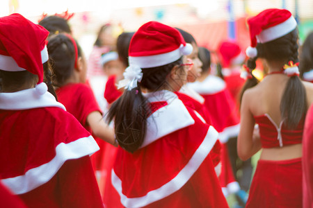 女孩穿着红主题服装 在圣诞晚会的初等学校 美丽的 白色的背景图片