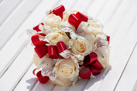 红丝带 蜜玫瑰和兰花的新娘花束 婚礼传统花卉组成 放在白木凳上举行结婚仪式 红色的 配饰背景图片