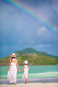 女士彩虹太阳帽加勒比海海滩上美丽的母亲和女儿 其背景彩虹令人惊叹背景