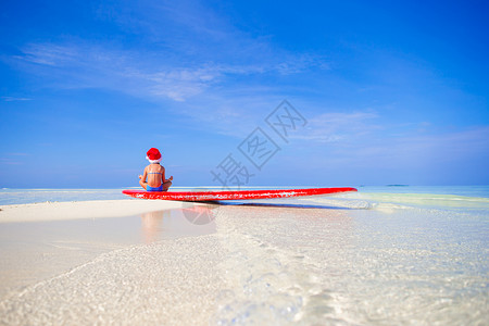 度假时在海滩上 戴着圣诞老人帽子的可爱小女孩 海岸 微笑背景图片
