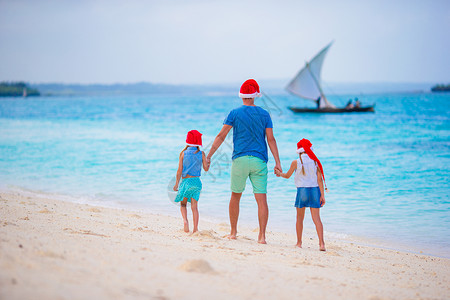 幸福的家庭在暑假圣诞老人的帽子 与年轻的四口之家一起享受海上旅行的圣诞假期 步行 喜悦背景图片