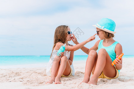 在热带沙滩上坐着一瓶防晒霜的小女孩 奶油 海洋背景图片