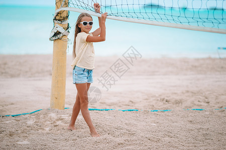 打排球的小女孩可爱的小女孩玩排球 在海滩上与球 活动 沙滩排球背景
