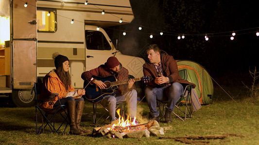 男人在营地火场周围 为朋友唱吉他歌 分享 棉花糖高清图片