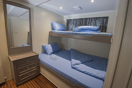 蓝色枕头豪华游艇客舱内 床头柜 卧室 双层床 抽屉 木头 舷窗 蓝色的背景