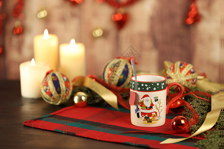 圣诞桌布上有空茶标签的圣诞杯 周围有松树枝 剪纸小饰品 点燃的蜡烛和悬挂在木制背景上的圣诞装饰 具有散景效果 锥体 味道背景图片