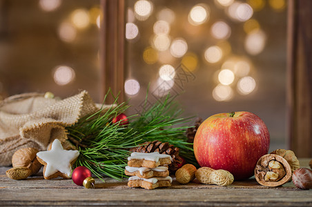 饼干袋圣诞假日背景 红苹果 饼干和芬果树枝 在灯光模糊的木柴上用圣塔袋袋装背景