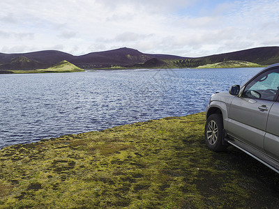 4x4路车停靠在位于Veidivotn湖的蓝火山坑湖和火山紫色及绿色山脉岸边 黑熔岩沙漠中冰岛中部地方高地流行捕鱼区背景图片