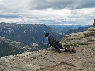 英西峰林躺在布道台悬崖上的 Lysefjord 峡湾的躺着的人 这是挪威著名的观点 喜怒无常的秋日 自然和旅游背景 假期和远足假期的概念背景