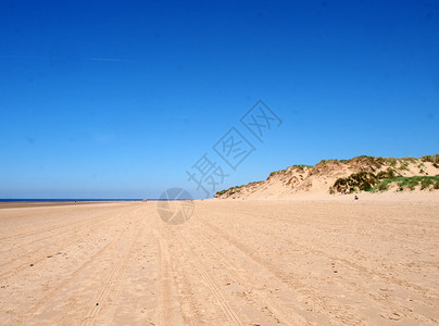 sefton在南港附近的Sefton海岸的宽沙滩上 有草覆盖沙丘和与蓝夏日天空相距遥远的无法辨认的人背景