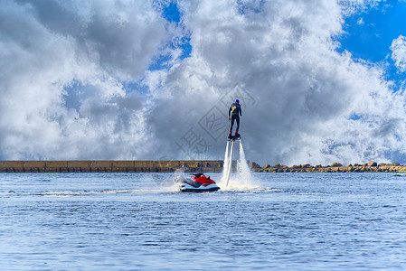喷气滑水船漂浮在港口河边的阳光明媚的暑假里 滑翔在水上活动飞天板上 速度 海滩背景