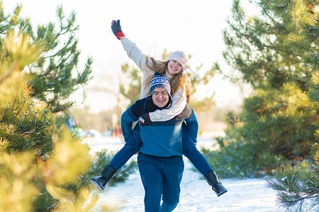 女孩在圣诞树的后面骑着一个男人 笑吧 玩得开心点 Y LAGHING 雪 滚雪球背景图片