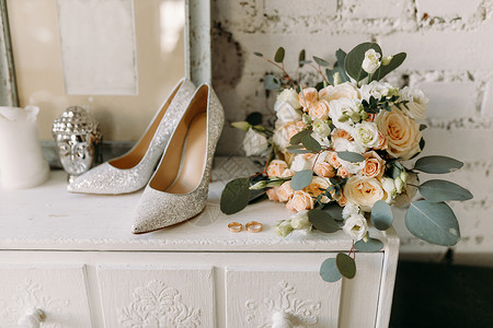 婚鞋和婚礼套装 结婚金戒指 婚纱上的嫁妆花束背景图片