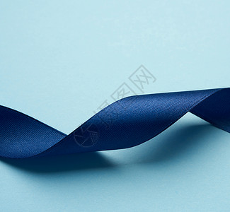 浅蓝色背景的深蓝丝带卷曲 闪耀 情人节 丝绸背景图片