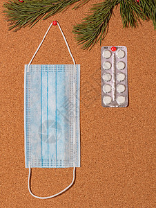 圣诞促销标签胶囊将医疗面具和白药片钉在用松树树枝装饰的corkwood通知板上 保健 圣诞节 新年庆祝活动 新的正常概念 陈述 广告背景