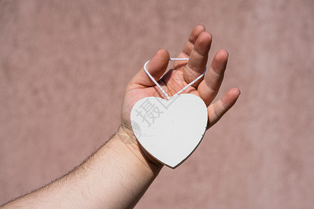 手握白木心形物体装饰的白色木制心脏 手捧心 空格处背景图片
