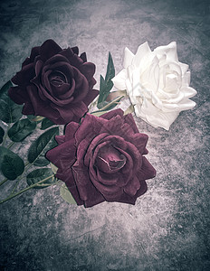 深色背景上的人造花三朵玫瑰背景图片