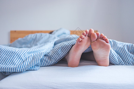 在床上享受清晨的快乐 把床内未露出的女性脚 毯子合上 晚睡 脚趾背景图片