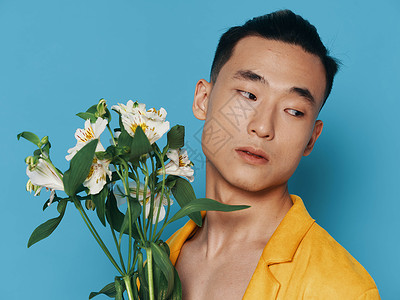 英俊的年轻帅哥 带着一束白色花束 在蓝色背景和亚洲外表上背景图片