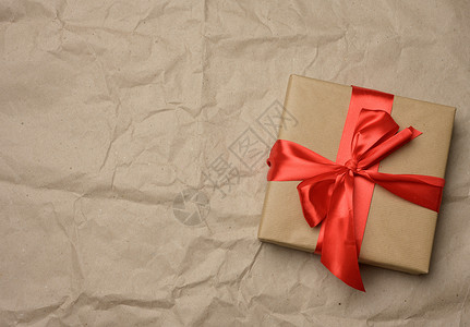 棕色纸面背面带丝绸红丝带的棕色纸板盒背景图片