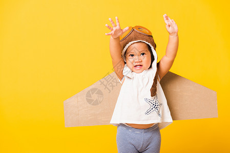 纸板机翼小男孩笑笑时 带着玩具纸板飞机机翼 戴着飞行员帽子玩耍和护目镜 成功 运动背景