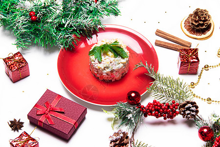 盘子里的礼物红色盘子里的奥利维尔沙拉 奥利维尔圣诞节 与沙拉的圣诞节布局 新年 假期 喜庆的菜 餐桌装饰 资本沙拉 菜单 自助餐背景