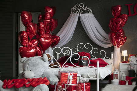 在内部的情人节 有用红色气球装饰的一张白色床的黑暗的卧室 浪漫的卧室内部 新婚之夜的房间背景图片
