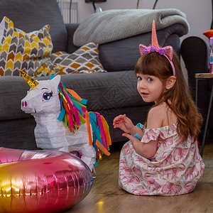 独角兽派对一个可爱的女婴坐在地板上 配着气球和独角兽皮纳塔 坐着 紫色的背景