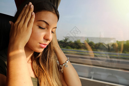 年轻女子在公共汽车旅行期间生病 晕车旅游妇女在公共汽车上头痛或恶心背景