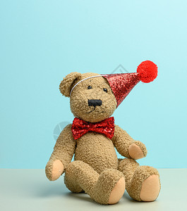 红帽子的棕色泰迪熊坐在蓝色背景上 工作室 浪漫的背景图片