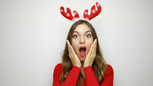 圣诞大卖 有驯鹿角的漂亮奇异女人 在白色背景上仰望着摄影机 情感 有趣的笑女肖像 新年的销售 销售量 惊喜背景图片