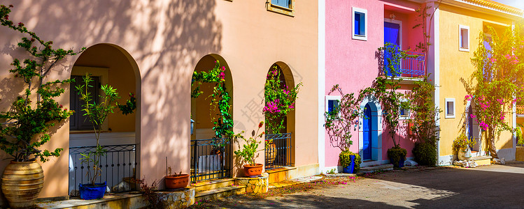 凯法利尼亚岛阿索斯的传统街道上有带鲜花的希腊房屋 Assos 村的传统色彩缤纷的希腊房屋 盛开的紫红色植物花 凯法利尼亚岛 希腊背景图片