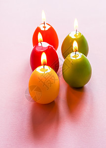 一组蜡烛传统的复活节装饰 粉红色背景中彩蛋形的一组明亮燃烧的石蜡蜡烛 早餐 庆典背景