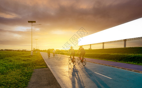 夏季防溺水宣传傍晚 运动员在路上骑自行车 靠近空白的广告牌 夕阳的天空 夏季户外运动健康快乐生活 骑自行车的人在自行车道上骑山地自行车背景
