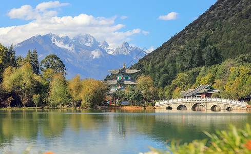 中国云南省丽江市玉泉公园黑龙潭上的玉龙雪山和索翠桥 蓝色的背景图片