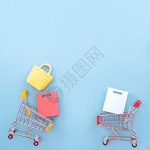 年度销售购物季的抽象设计元素概念-带纸袋的迷你黄色手推车 在柔和的蓝色背景顶视图平躺上隔离 多于 周年纪念日背景图片