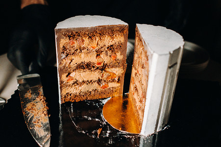 惊人的蛋糕 黑色背景上有令人惊叹的馅料的切片巧克力婚礼蛋糕 白巧克力大蛋糕 多层次 庆典背景图片