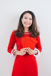 越南妇女传统艺术节服装Ao Dai 持有红钱袋背景图片
