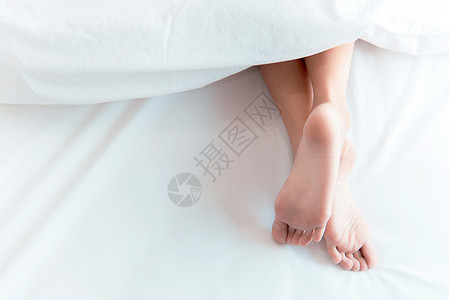 脚长睡和放松概念 假期和节假日主题 妇女用白毯子在床上站着的女士脚背景