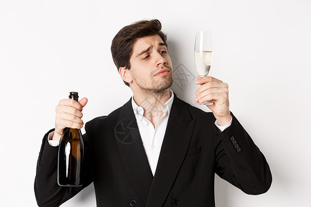 穿着时装 尝香槟 看玻璃 站在白色背景下站立的有魅力的男人近距离接近 快乐的 庆典背景图片