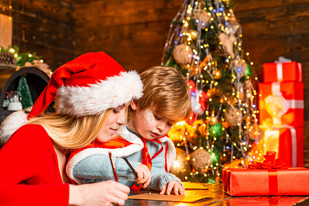 妈妈和孩子给圣诞老人写一封信 上面写着圣诞礼物的愿望清单 圣诞室内 圣诞快乐和新年快乐 明亮的新年室内概念背景图片