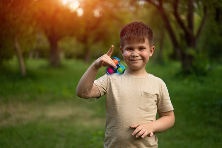 手指微调器有趣的微笑男孩在阳光明媚的日子里在公园里玩微调 6 岁的家伙手里拿着一个微调器 户外与儿子背景