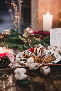 靠近竹枝的圣诞盘子上放着草莓的果馅奶酪卷的特写 在一张木桌上的圣诞节早餐 香草 烹饪背景图片