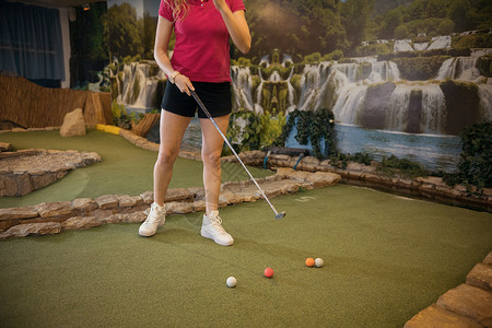 假期课程一个在室内打小型高尔夫球的年轻女子背景