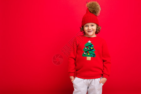 有卷卷卷卷的酷男孩 红色背景 穿着毛衣和圣诞树 微笑 年轻的图片