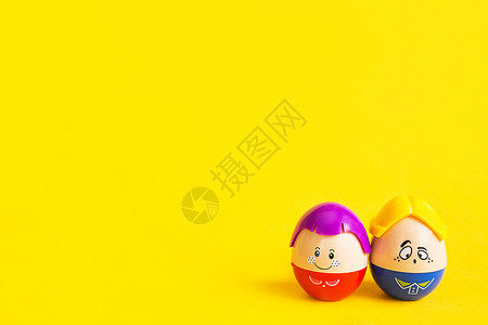 两个彩蛋两个有趣的鸡蛋男孩和女孩 脸上有黄色背景 — 复活节 春天 儿童玩具——象征男女情侣 爱情 家庭 复制空间背景
